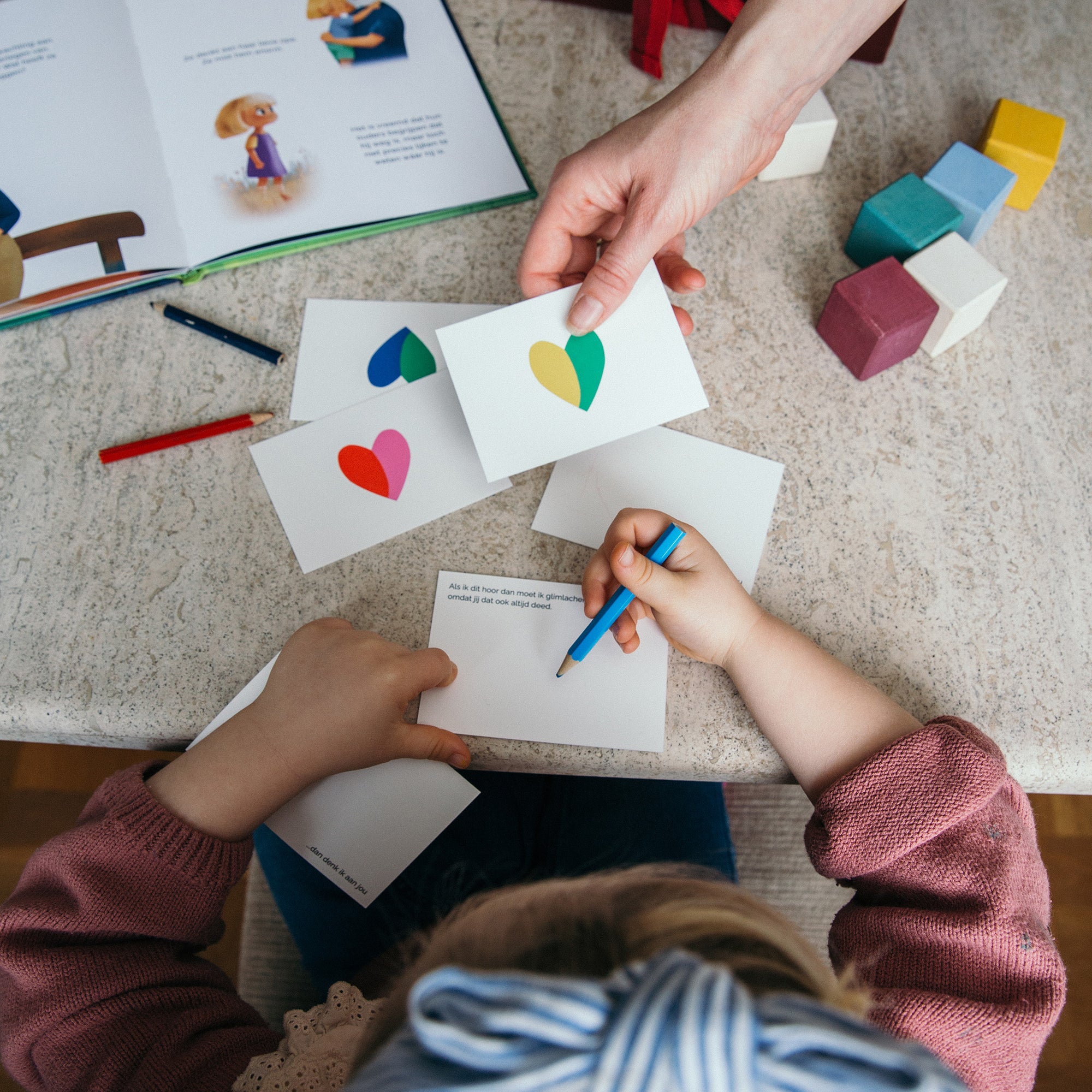 Een kind kleurt hartjes op de 'Thinking of You' notitiekaartjes, bedoeld om herinneringen te bewaren en gevoelens te uiten.